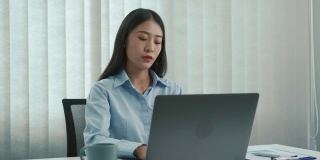 年轻的亚洲女性在下午的办公室里打哈欠。