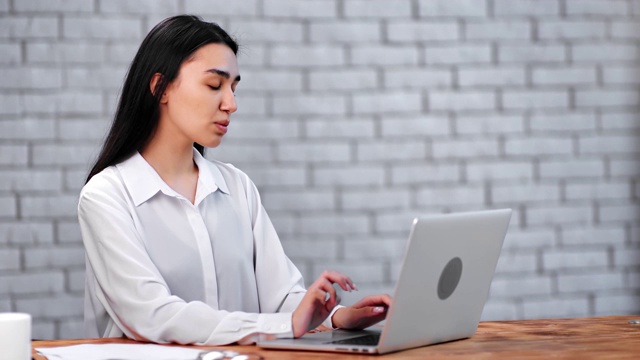 沉思的亚洲女商人在办公室用笔记本电脑聊天。由RED Raven 4k电影摄像机拍摄