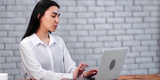 沉思的亚洲女商人在办公室用笔记本电脑聊天。由RED Raven 4k电影摄像机拍摄