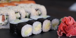 一套寿司卷旋转桌子上的黑色背景特写。