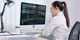 4k视频片段的年轻亚洲女性程序员阅读和工作在电脑上编码开发网站设计和开发技术