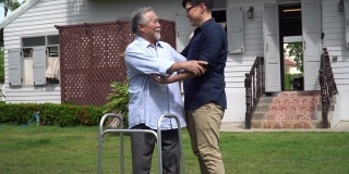 亚洲老人带着沃克和成年的儿子一起走在加登的家里。老人残疾行走和照顾年轻人帮助在后院。保健家庭生活方式