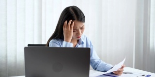 一段女商人在办公室用笔记本电脑工作时看起来很焦虑的4k视频
