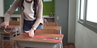 亚洲女教师在课桌上用交叉的符号批改红字