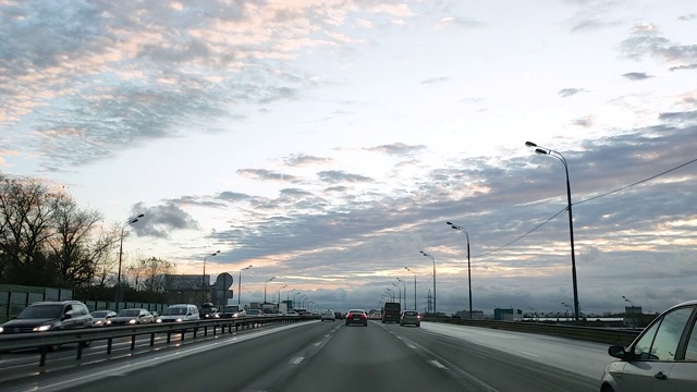 俄罗斯。透过挡风玻璃观看一辆汽车在一个有交叉路口的八车道道路上行驶，汽车在这条道路上行驶，迎面的车道上已经形成了交通堵塞。