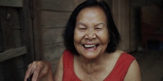慢动作的泰国老妇人圆领无袖领在老木屋里笑