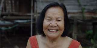 泰国老妇人在圆领无袖领子在老木头的家笑