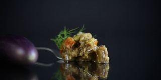 煮熟的夏季茄子鱼子酱与蔬菜在黑色的背景