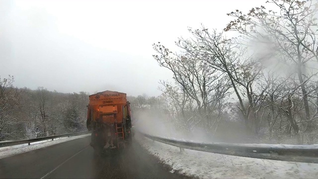 后视镜扫雪机服务卡车和撒盐砂砾路面，以防止结冰在暴风雪的冬天的日子，缓慢的动作