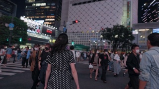 一名年轻女子在夜间走过涉谷十字路口视频素材模板下载