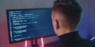 IT专业程序员正在输入代码。开发人员在电脑上工作。黑客深夜在霓虹灯下入侵。