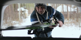 一个人从汽车后备箱里拿出滑雪板。
