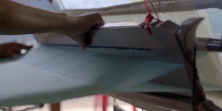 慢动作妇女在织布机编织手工织物。纺织织造。用传统手工织布机在棉线上织造。纺织或布料生产。亚洲文化。