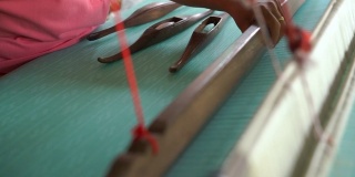 在织布机上工作的妇女，编织手工织物。纺织织造。用传统手工织布机在棉线上织造。泰国的纺织或布料生产。亚洲文化。