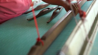 在织布机上工作的妇女，编织手工织物。纺织织造。用传统手工织布机在棉线上织造。泰国的纺织或布料生产。亚洲文化。视频素材模板下载