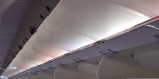 飞机上空的机舱行李舱。从飞机空调吹出的冷热空气冷凝雾。飞机顶灯带雾。