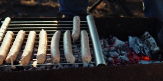 特写男子在院子里的烤架上烤香肠。用炭火煮肉。