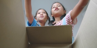 两个亚洲女孩帮助父母把东西放进盒子和关闭盒子搬迁前的日子。家居装修和搬迁概念。慢动作镜头。