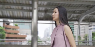年轻的亚洲女商人看手表和速度步行附近的办公楼。迷人的亚洲商务女孩在匆忙和匆忙的会议。中国韩国美女上班迟到- 4K高清视频