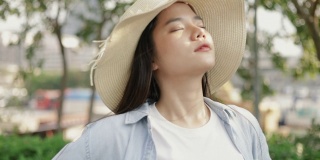 美丽的亚洲女人戴着一顶复古的帽子，悠闲地享受着宁静的日落。