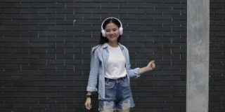 美丽的亚洲女人戴着耳机听音乐和跳舞。