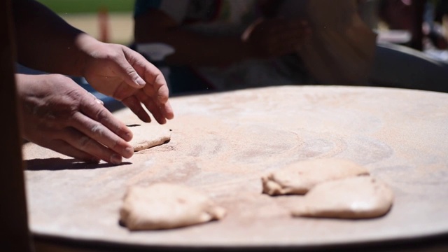 亚美尼亚面包卷的烹饪工艺。面包师在桌上用擀面杖揉面。靠近手。