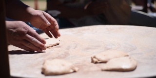亚美尼亚面包卷的烹饪工艺。面包师在桌上用擀面杖揉面。靠近手。