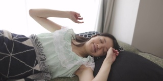 清晨，年轻女子穿着睡衣躺在床上