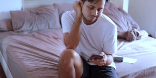 一名亚洲男子在床上使用智能手机