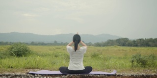 美丽的白人女性坐在冥想姿势姿势瑜伽调呼吸平衡在美丽的山景在早上。
