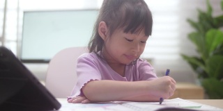 亚洲女儿在家里用数字平板电脑学习在线课程