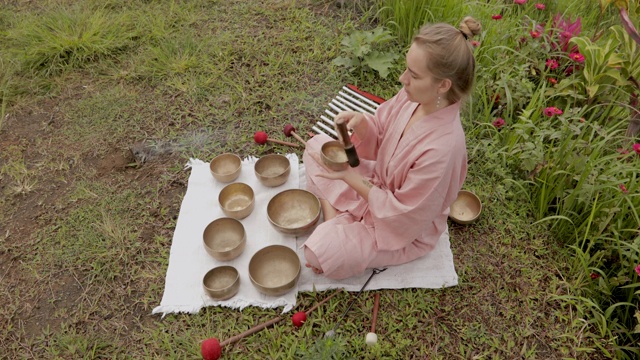 身穿粉红色和服的白发少女在唱歌钵上玩耍