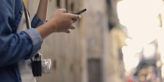 年轻的亚洲女性旅行者手持智能手机，在泰国曼谷的一条小街上查看地图。