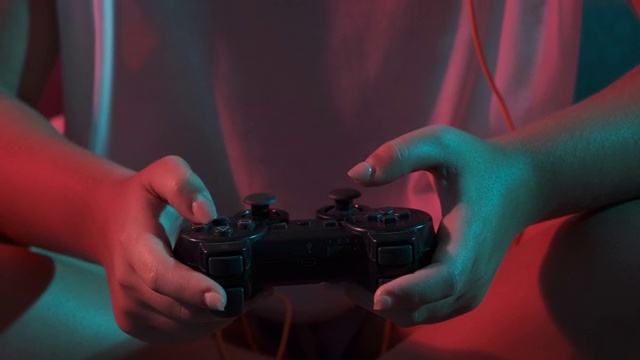 女人的手与游戏控制台控制器的特写，而玩。彩灯