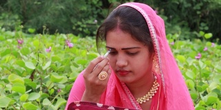 一位印度美女坐在花园里面带微笑，穿着Rakhdi(马尔瓦里新娘称之为maang tikka)。