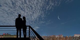男人和女人站在阳台上，以夜市为背景。hyperlapse