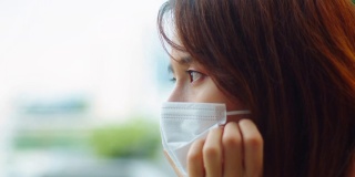 在冠状病毒或COVID-19大流行期间，不快乐的年轻亚洲女性戴着医用口罩站在屋顶上进行自我隔离，感到无聊、压力、抑郁和孤独