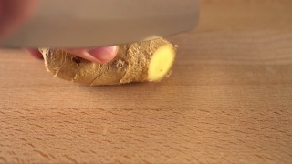 一名男子用刀将多汁的生姜切成块。在一块木板上。视频素材模板下载