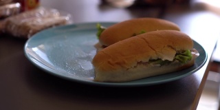 灰色桌子上的一个海蓝宝石盘子里放着新鲜的三明治。