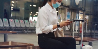 在新冠肺炎大流行期间，女商人在机场候机楼戴口罩，与朋友通电话，保持社交距离。