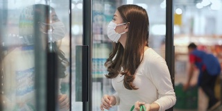 女人戴着口罩在超市购买冷冻产品