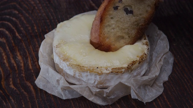 把烤面包蘸到卡门培尔奶酪里。极端特写镜头
