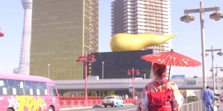 亚洲妇女穿着传统的日本和服，拿着红色的纸伞