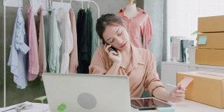 迷人的年轻亚洲女性小企业主用手机与客户交谈，接受购买订单。