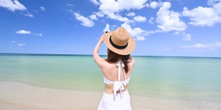 穿着比基尼的女人用智能手机拍摄蓝天和热带海滩