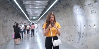 年轻美丽的亚洲女人用智能手机导航走在地铁站里。有魅力的女孩用手机和互联网进行社交媒体或在线信息。无线技术与城市生活理念。