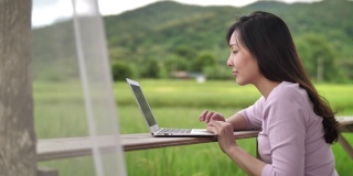 亚洲女性使用笔记本电脑在度假旅行中远程工作