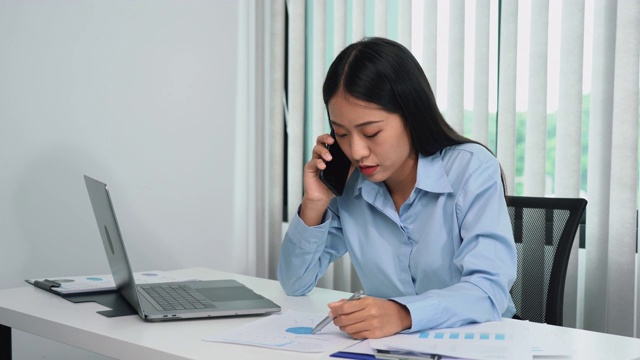 亚洲经理正在与一名员工通电话，对办公室错误的文书工作感到愤怒。