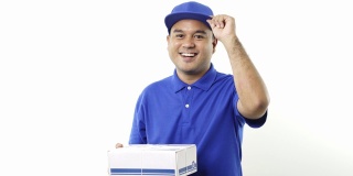 微笑的年轻亚洲快递员在蓝色制服显示大拇指举着包裹纸箱在孤立的白色背景。4 k决议。