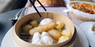 年轻女子打开篮子里的饺子放在桌上点心，传统的中国饺子在传统的木篮子里